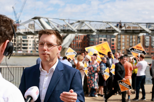 Rob Blackie pictured with a microphone on a bridge with Liberal Democrat activists