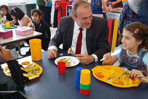 Ed Davey sharing a school meal with some children
